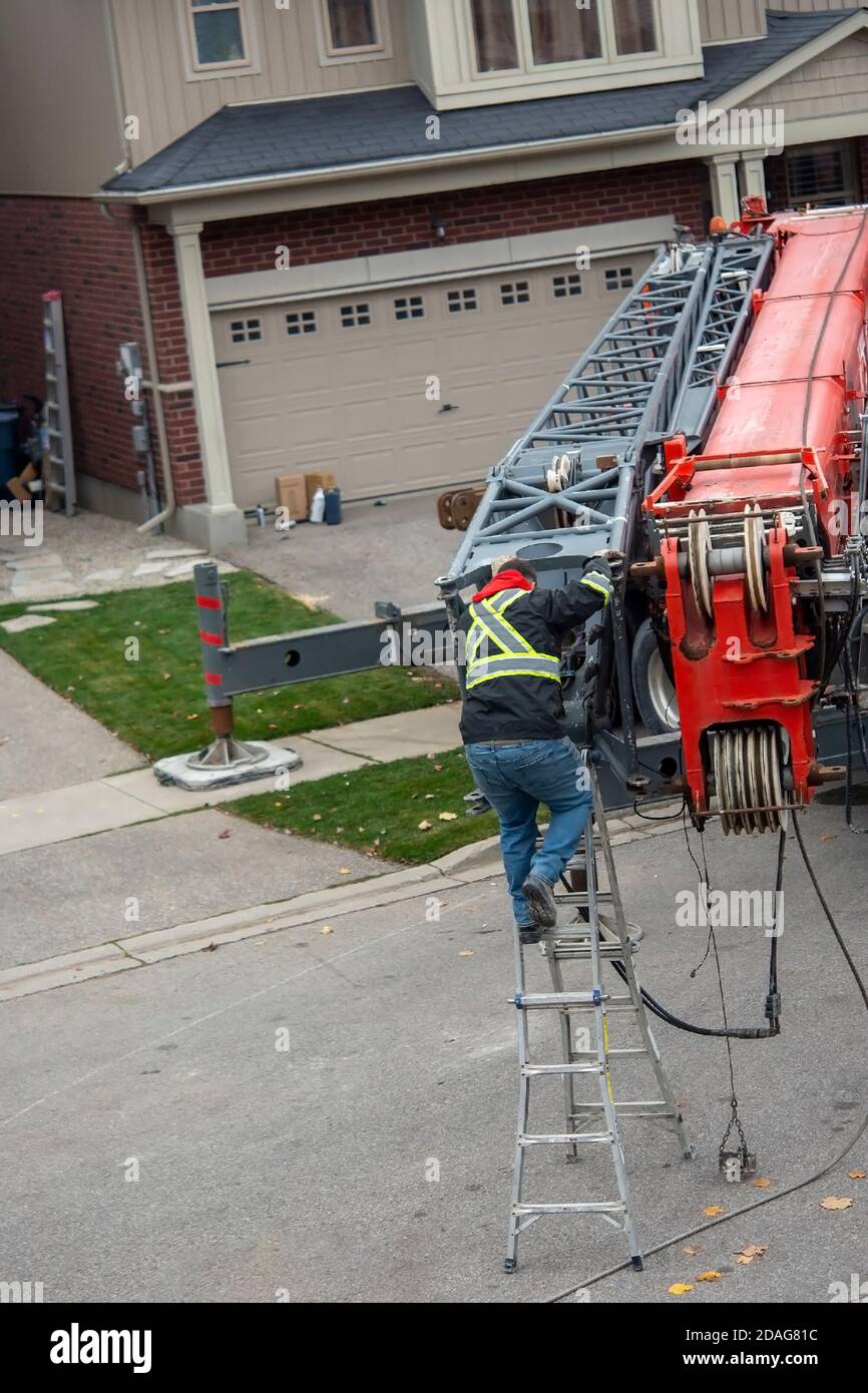 The crane operator prepares the crane for work, attaches an additional section by extending the boom Stock Photo