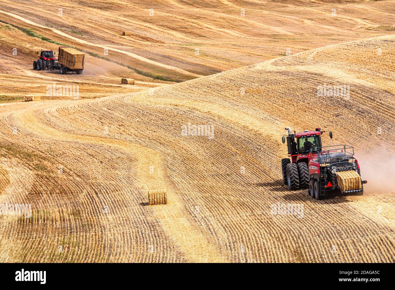 CaseIH 4WD wheeled tractor pulling a large rectangular baler to bale