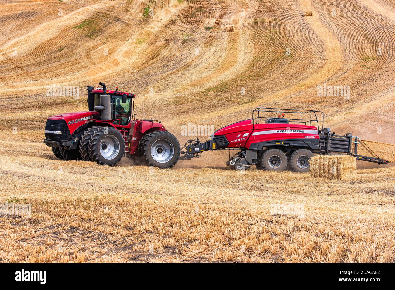 CaseIH 4WD wheeled tractor pulling a large rectangular baler to bale
