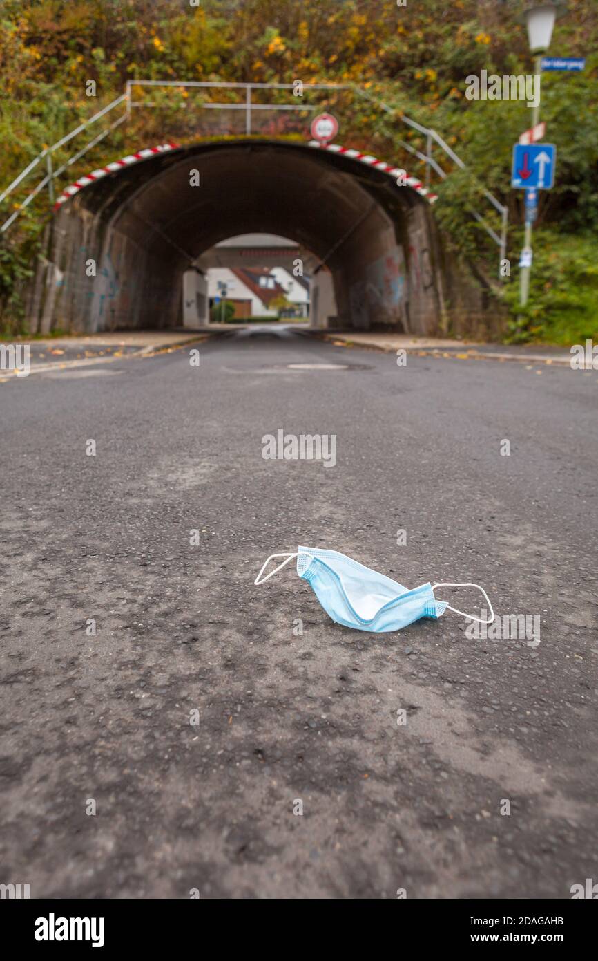 An abandoned face mask in front of a tunnel symbolizing the Corona or Covid-19 pandemic Stock Photo
