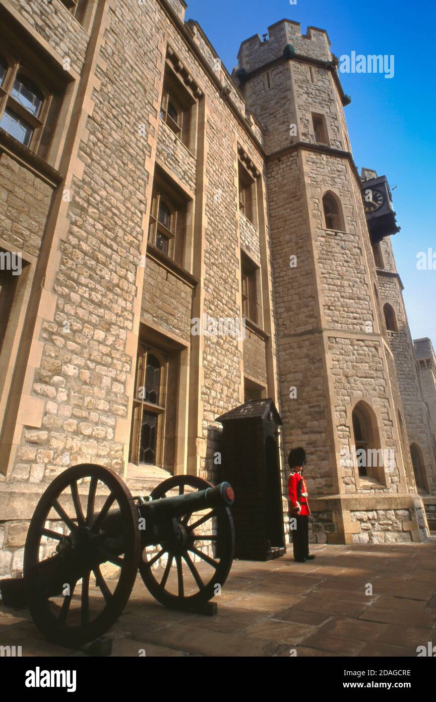 GUARD TOWER OF LONDON CROWN JEWELS HOUSE GRENADIER GUARD BUSBY ceremonial guard in traditional red tunic and busby on guard at the Crown Jewels House with historic army cannon field gun in foreground at the Tower of London LONDON UK Stock Photo