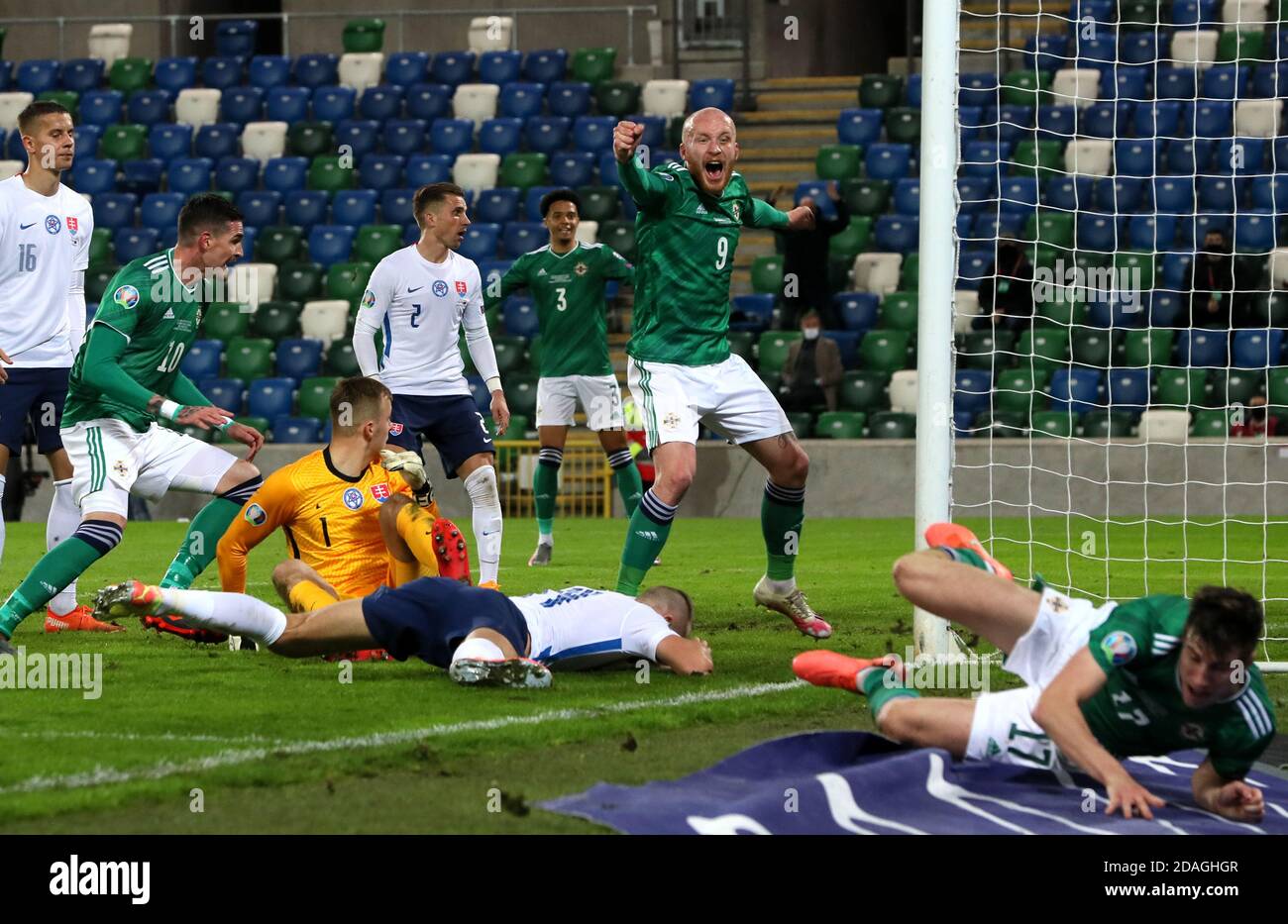 Norther Ireland's Liam Boyce (centre right) celebrates after Slovakia's Milan Skriniar (floor) scores an own goal during the UEFA Euro 2020 Play-off Finals match at Windsor Park, Belfast. Stock Photo