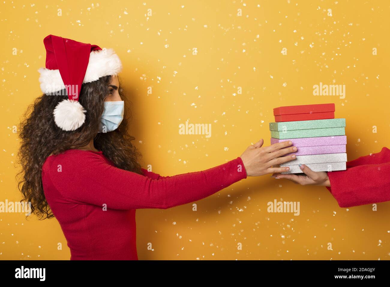 Happy girl receives Christmas gifts from a friend. Yellow background Stock Photo