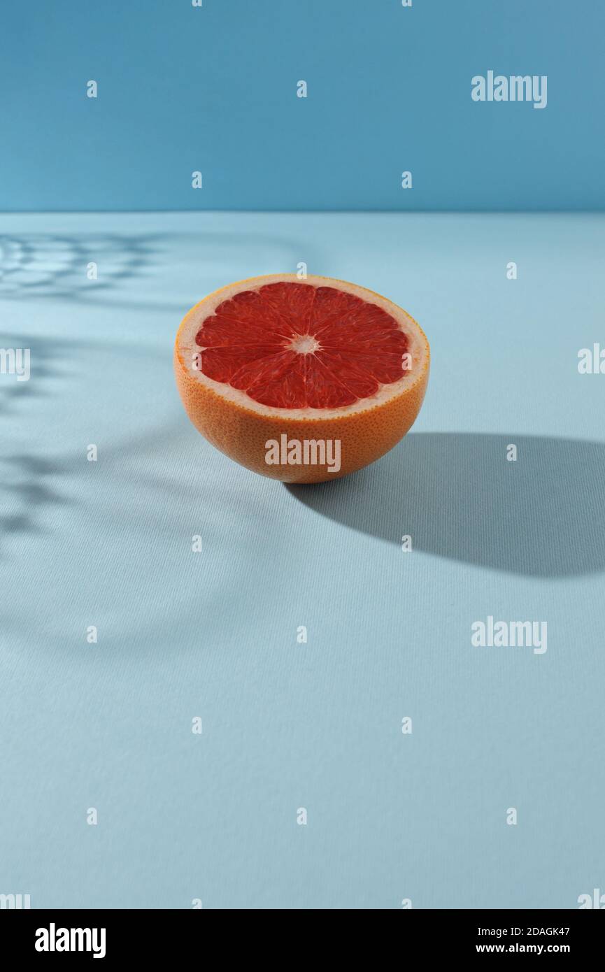 Creative  background  with slice of grapefruit  and shadows in minimal style. Creative summer layout.Vertical orientation with space for text. Stock Photo