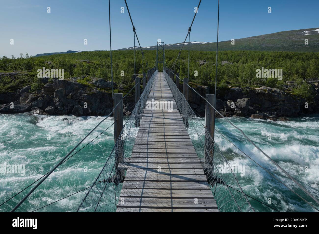 Hanging bridge over flowing water of Vuojatädno river along Padjelantaleden Trail, Lapland, Sweden Stock Photo