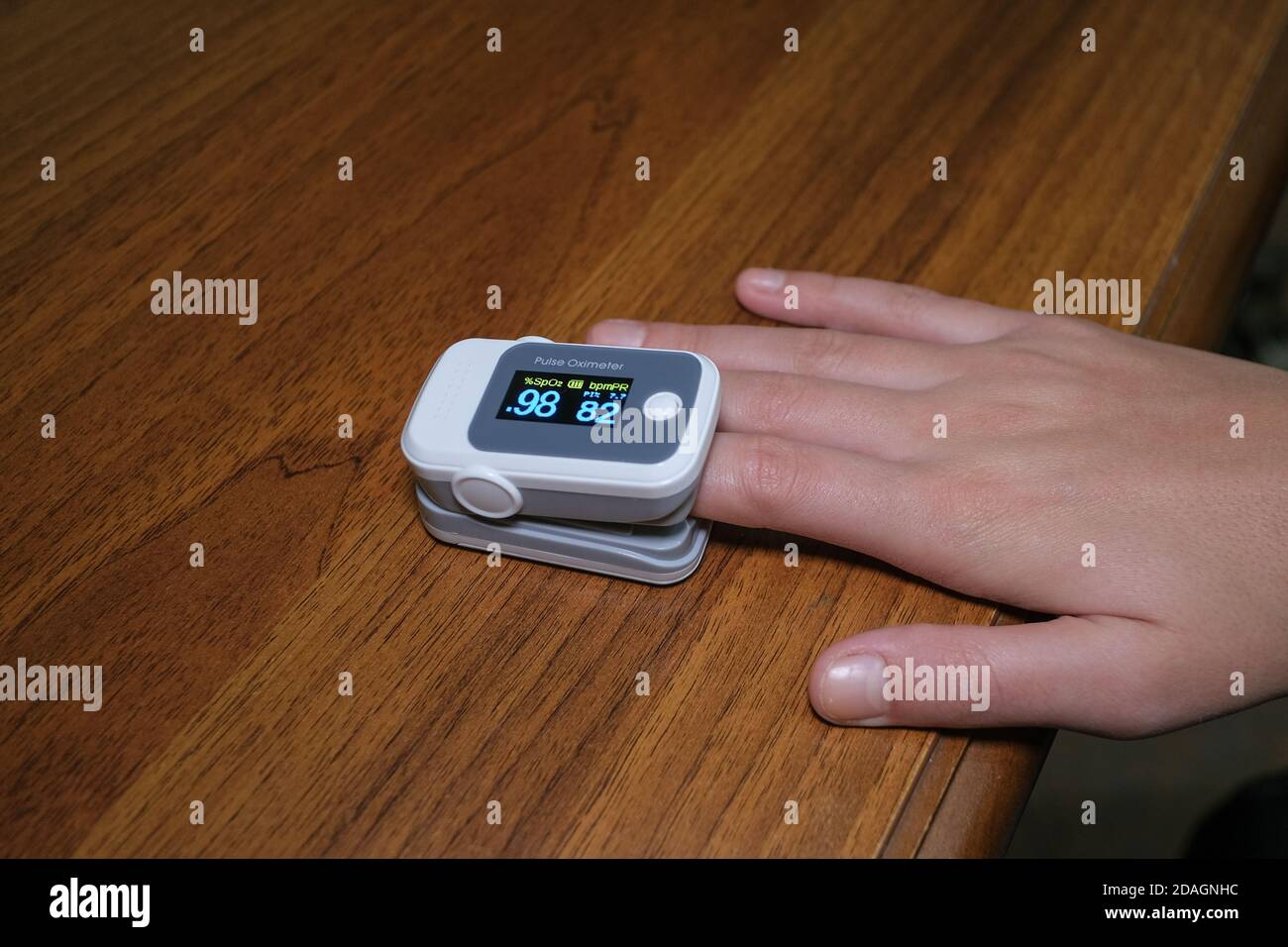 Young woman using pulse oximeter to measure oxygen saturation in covid19 pandemic disease,medical home monitoring treatment Stock Photo