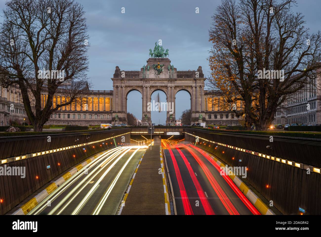 Open section of a road running underneath Park du Cinquantenaire in central Brusseles, Belgium, at dusk. Light trails. Stock Photo