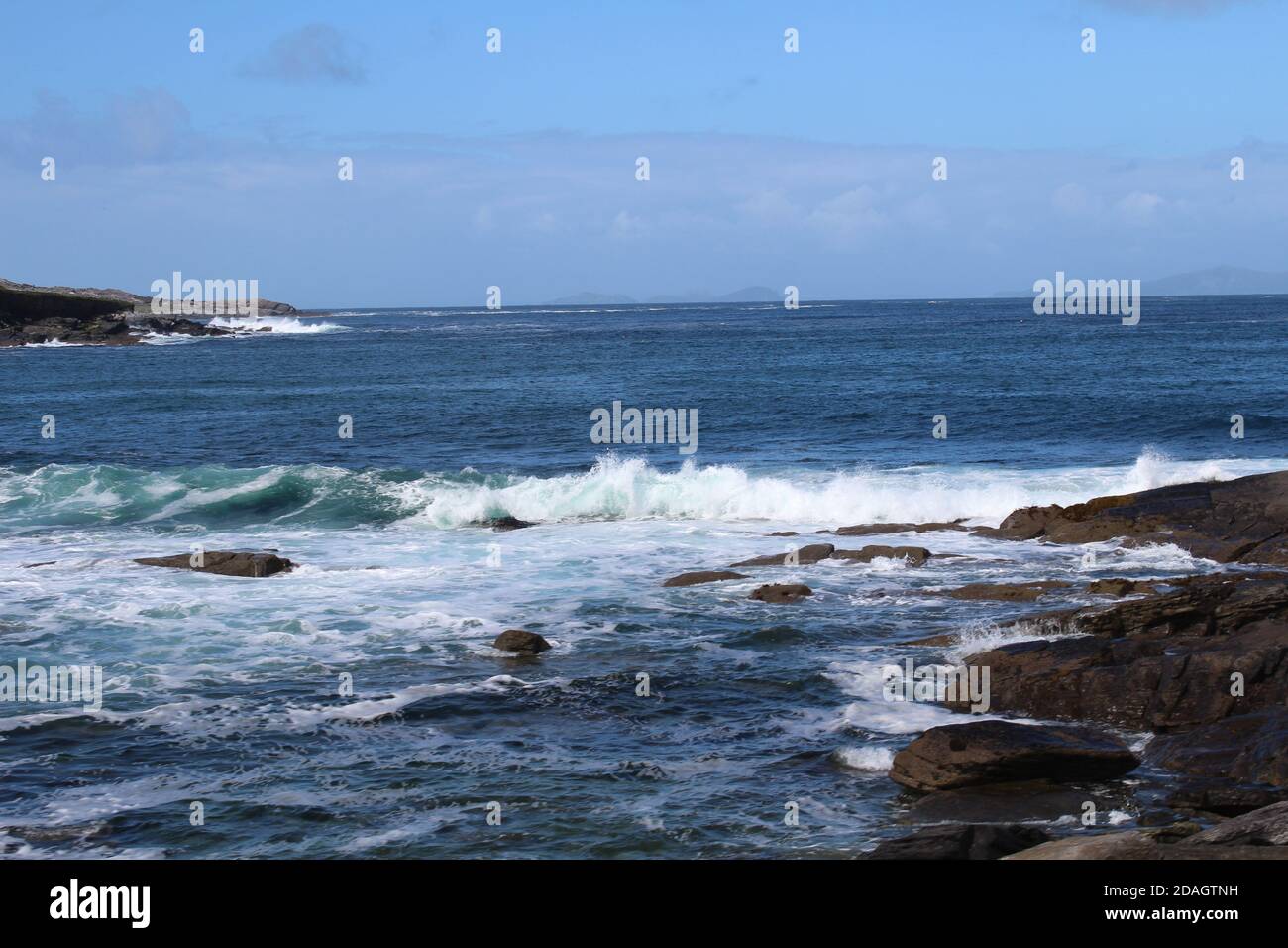 Landscape of the sea surrounded by rocks under a blue cloudy sky ...