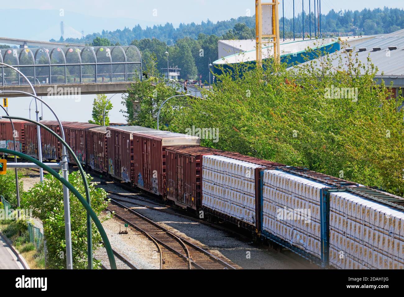 Freight train rumbling down the tracks through a business section of New Westminster, B. C., Canada. Stock Photo