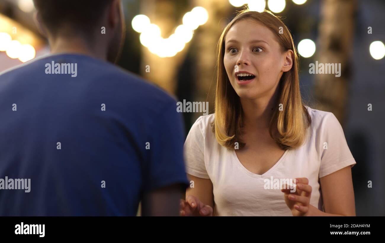 Cute girl telling a story to her friend with bright emotions. Stock Photo