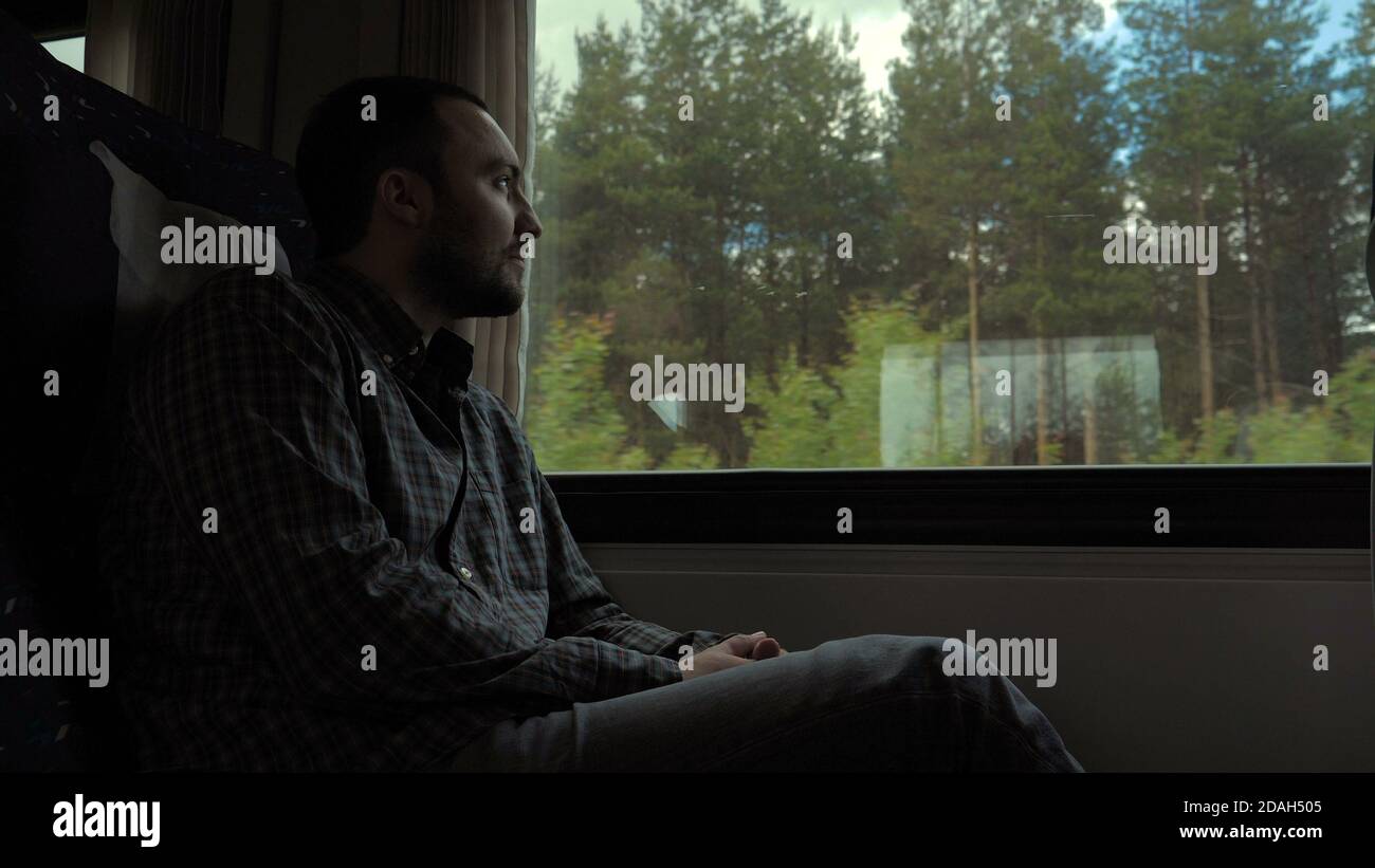 Sad young man looking through the window Stock Photo