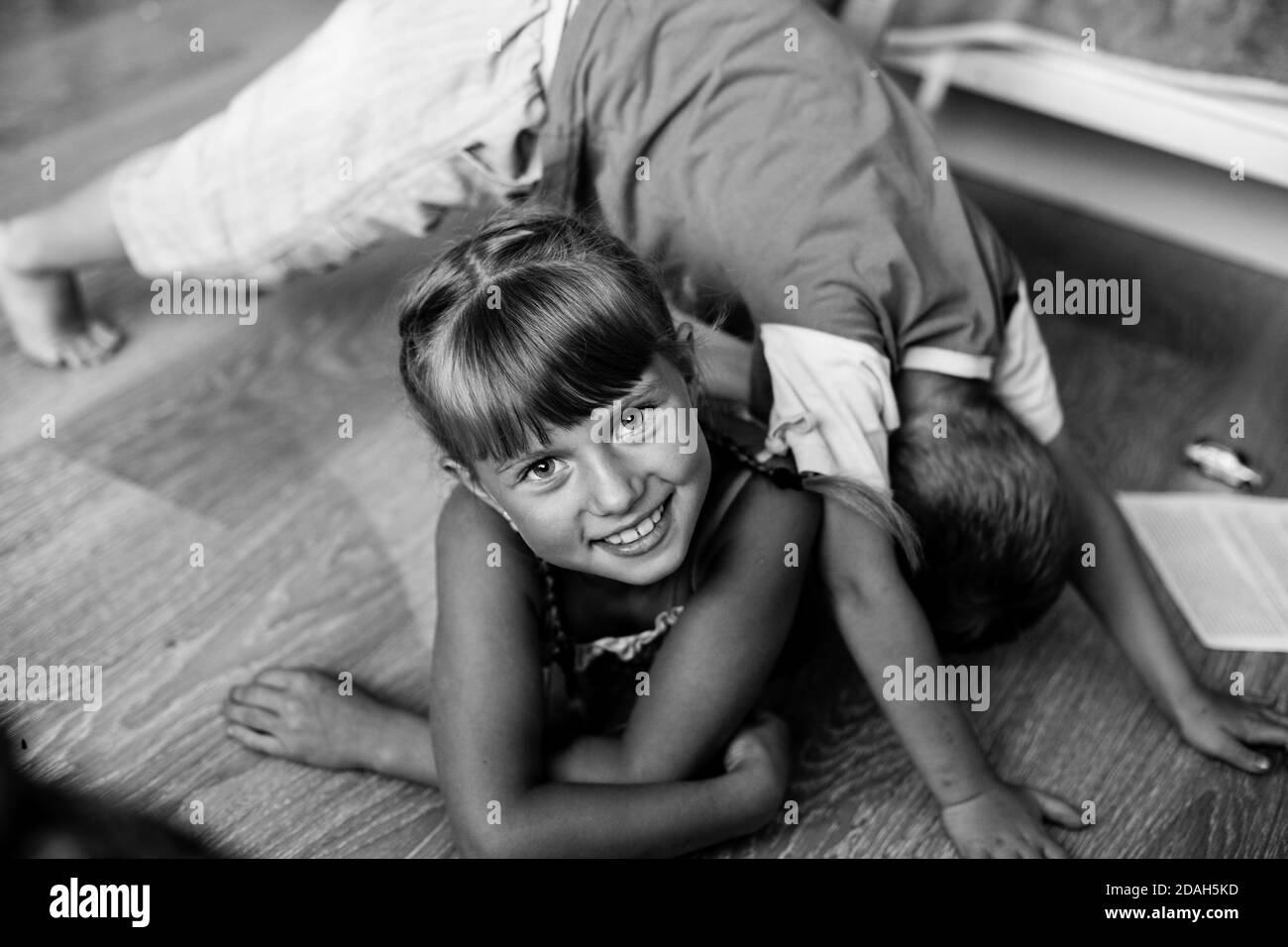 Little girl mischievously playing with her brother. Black and white photography. Stock Photo