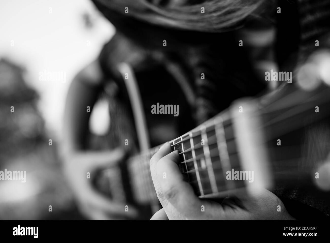Fingers on the strings girl playing acoustic guitar. Black and