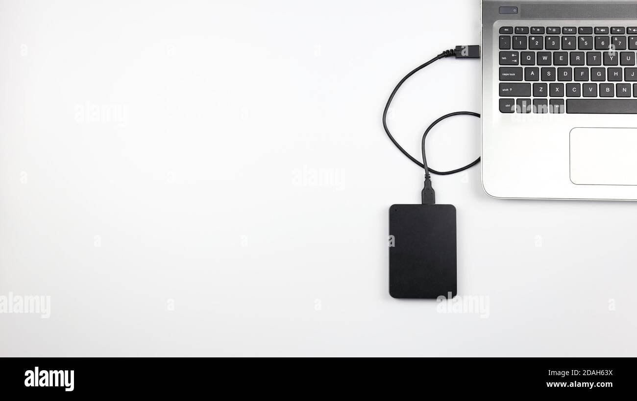 External hard drive connected to laptop on white surface. Concept for office, business, education and presentation Stock Photo