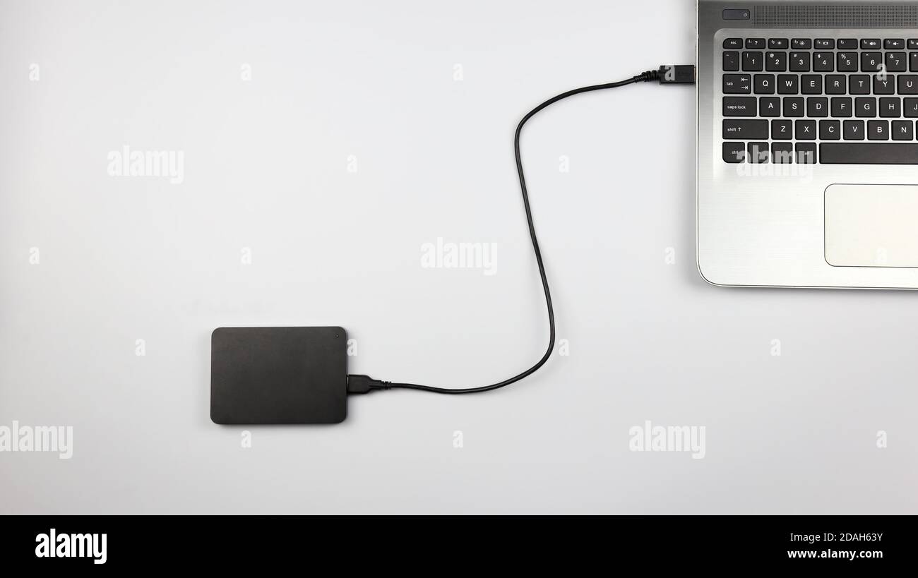 External hard drive connected to laptop on white surface. Concept for office, business, education and presentation Stock Photo
