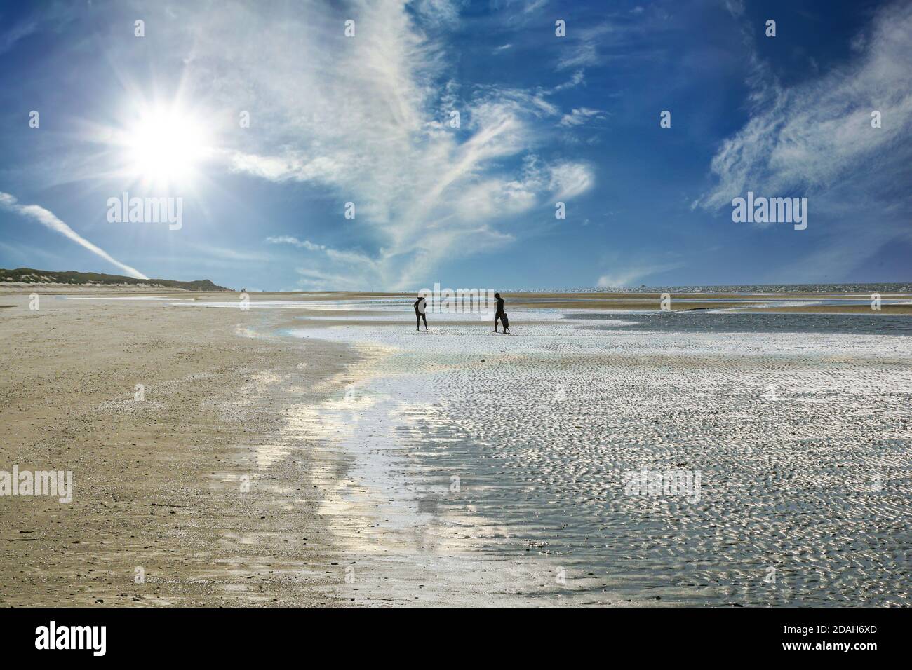 Beach and seacoast with cloudscape with family silhouettes in distance. Extreme long shot. Stock Photo