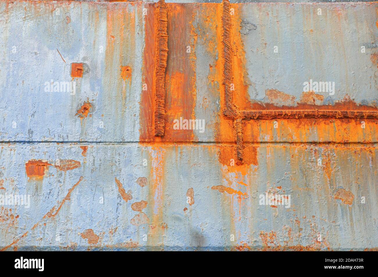 Concrete wall with rust on metal and chipped paint. Abstract. Low angle view. Stock Photo
