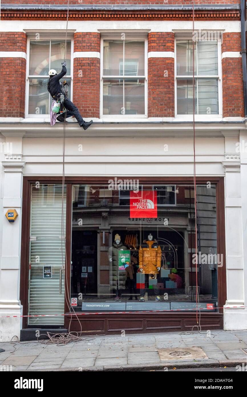 London, UK. 12th Nov, 2020. A man hangs on a rope in London's Covent Garden  while