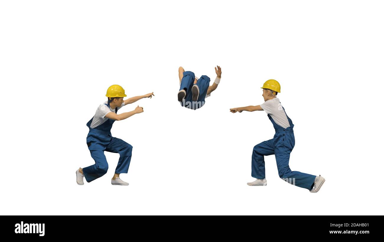 Three young construction workers in hard hats synch dancing look Stock Photo