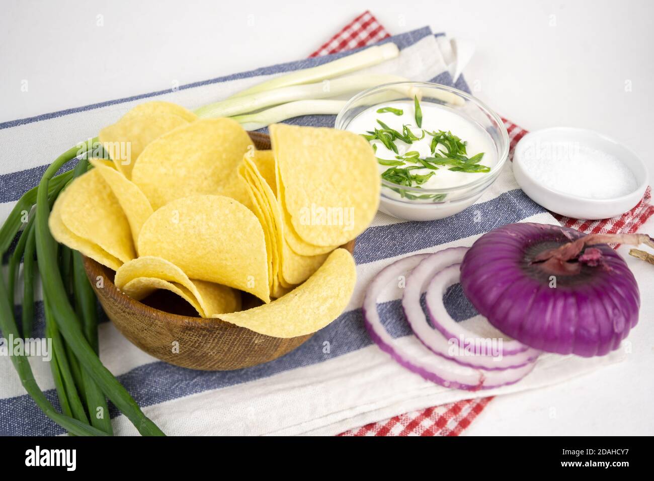 Chips in a wooden bowl with sour cream and green onion. Stock Photo