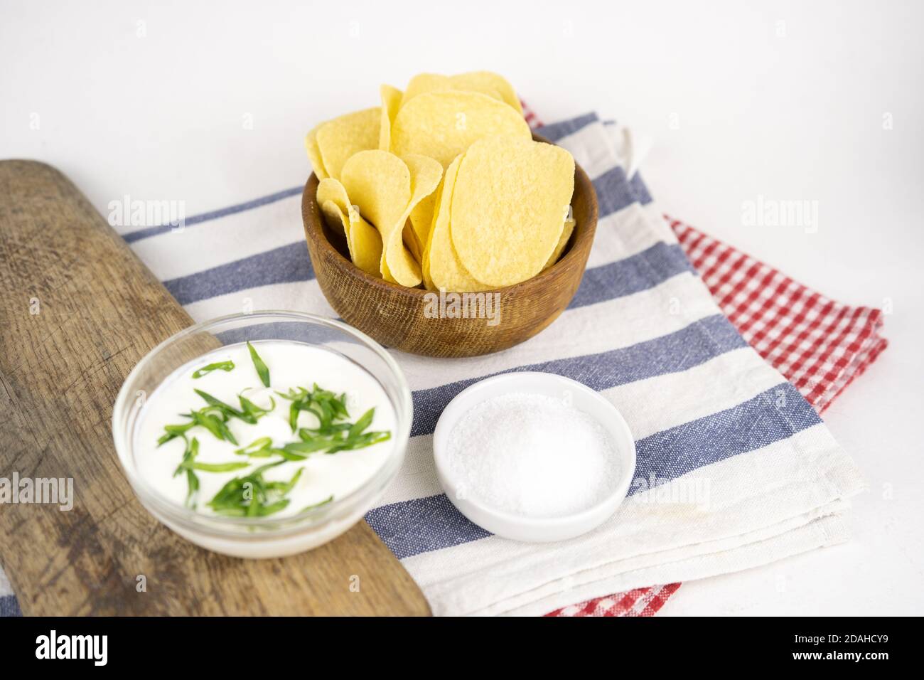 Chips in a wooden bowl with sour cream and green onion. Stock Photo