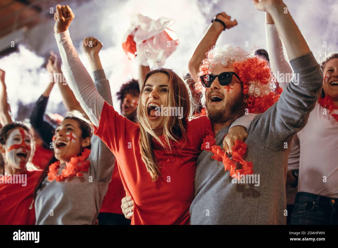 Excited sports fans at live game chanting and cheering for their team. Young people watching football match chanting to cheer English national team. Stock Photo