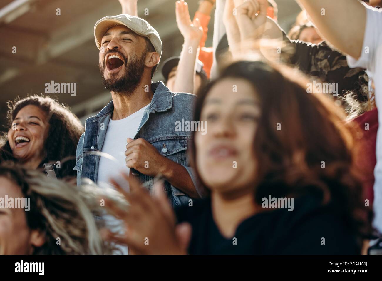 Group of happy fans cheering for their team victory. Friends having fun while watching a match at stadium. Stock Photo