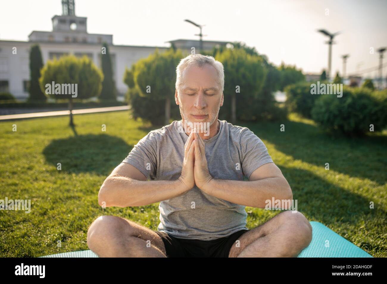 Grey-haired man practicing yoga outside, hands in namaste Stock Photo ...