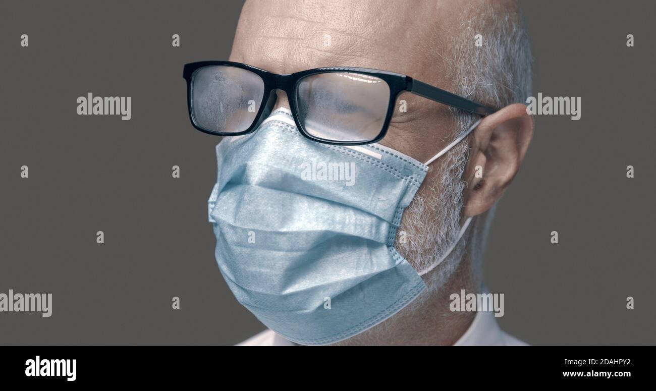 Senior man with glasses fogging up while wearing a protective face mask