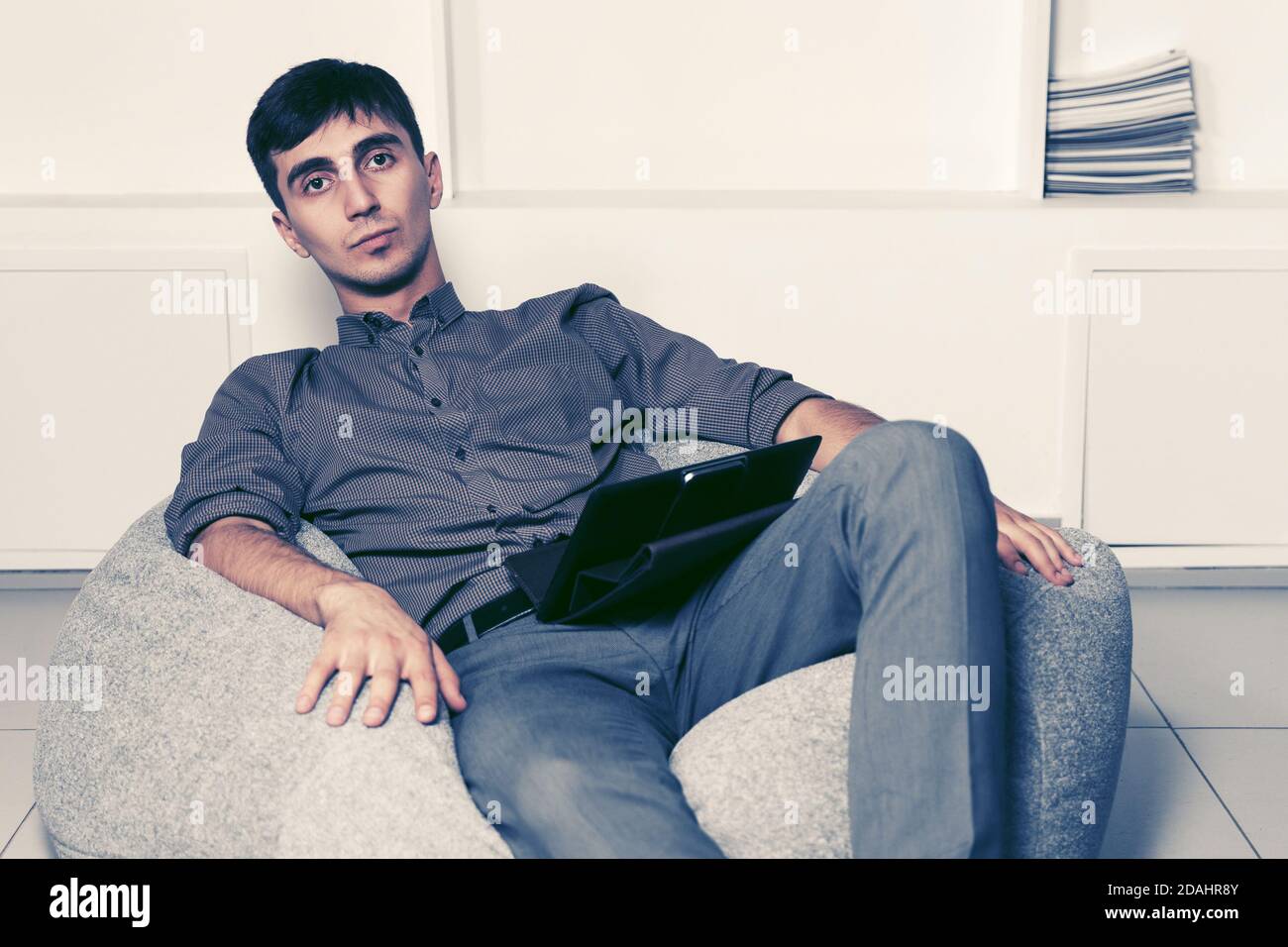 Trendy young man sitting chair hi-res stock photography and images - Alamy