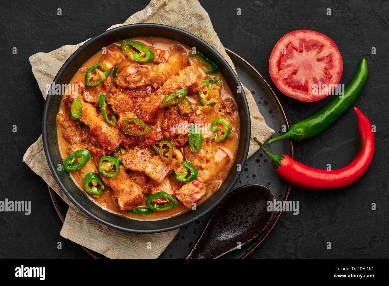 Bicol Express Stew in black bowl on dark slate table top. Filipino cuisine spicy pork belly