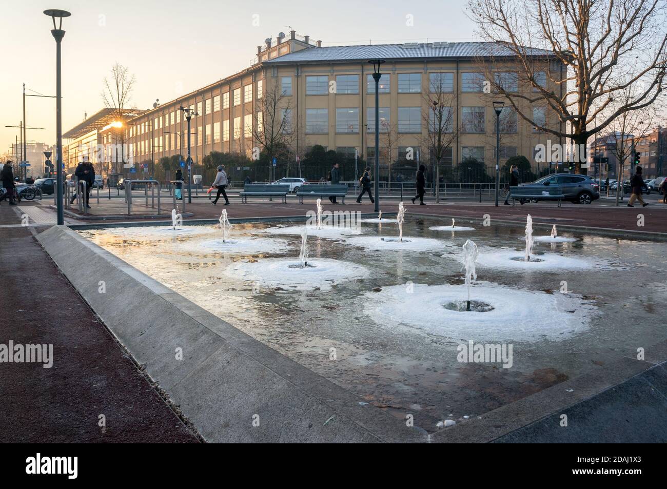 Frozen fountains on the background of walking people and buildings on the street in the winter, in a residential area of Portello of Milan. Stock Photo