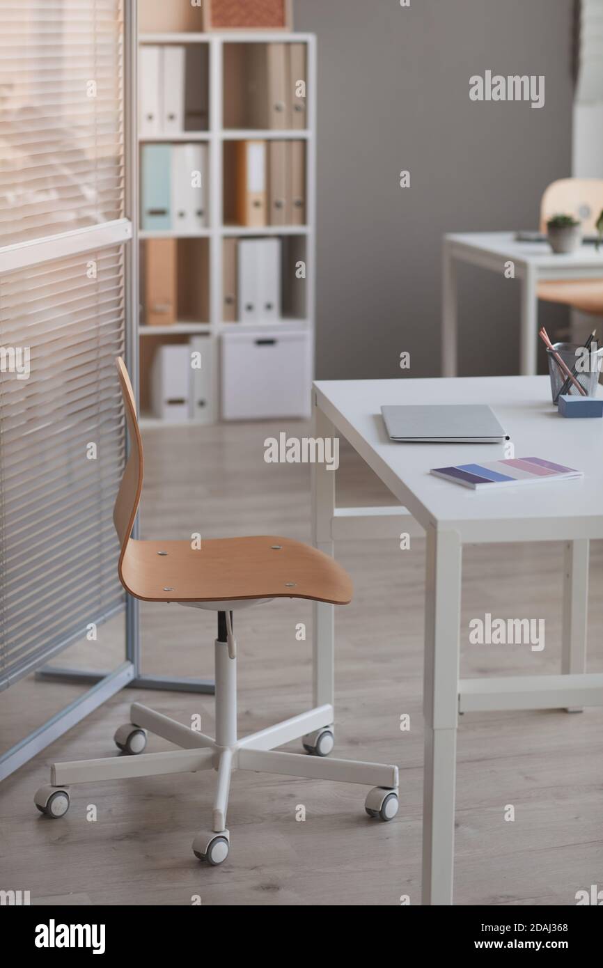 Image of empty table with laptop on it and chair at modern office Stock