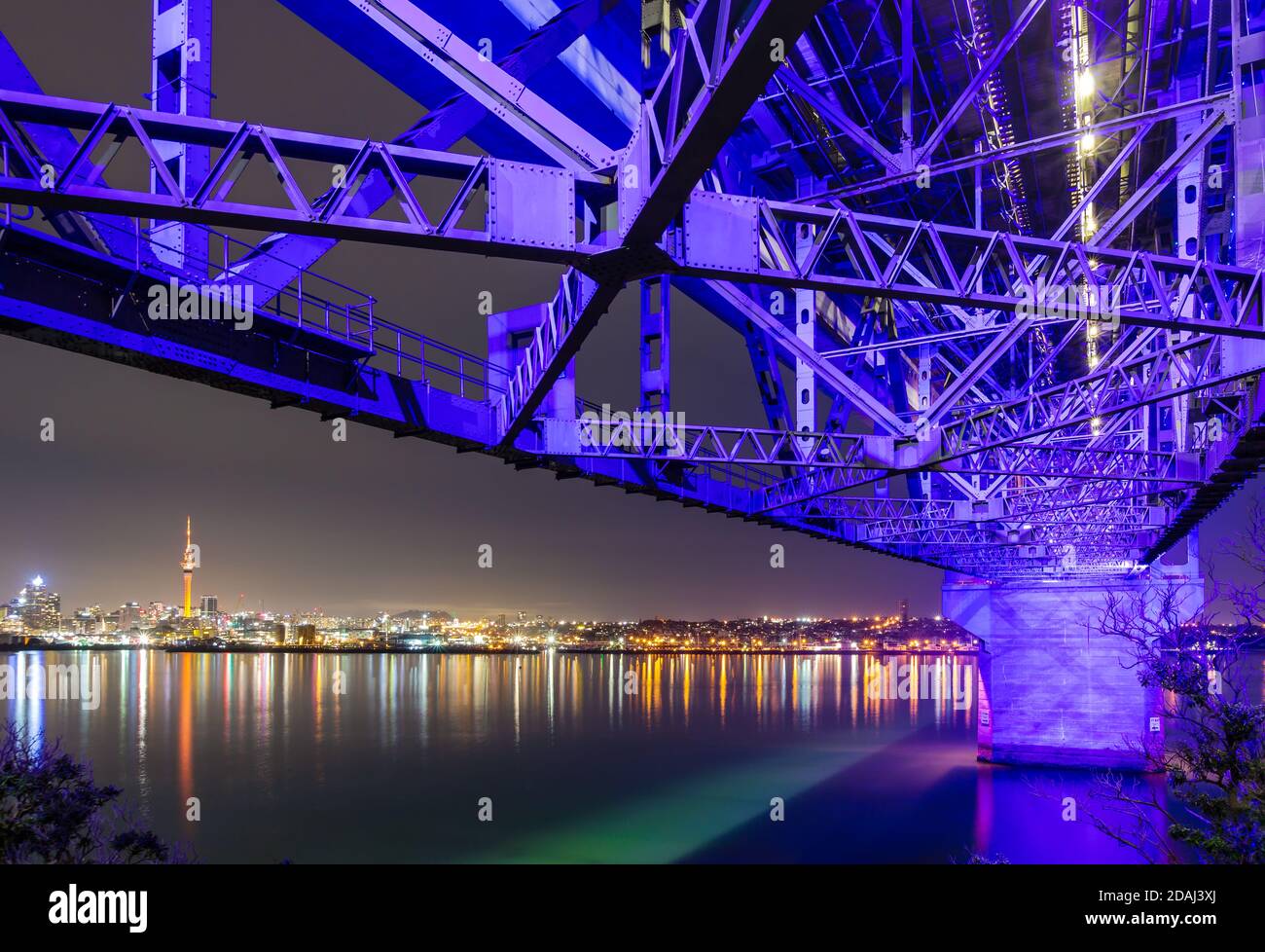 The skyline of Auckland, New Zealand, at night, viewed from beneath the Auckland Harbour Bridge Stock Photo