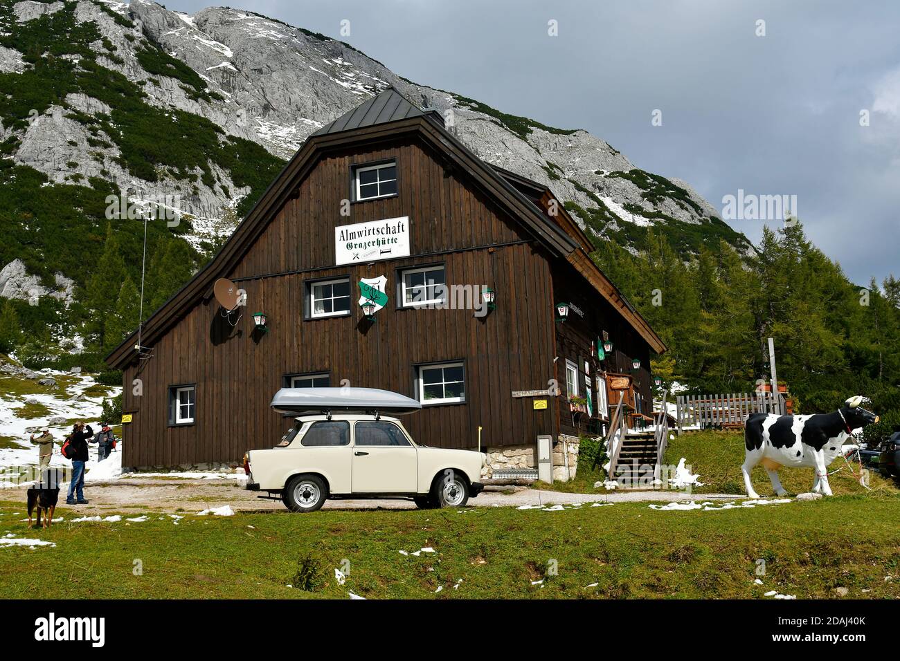 Tauplitz, Austria - September 24, 2017: Unidentified tourists, plastic cow and vintage car Trabant 601 the nickname was Trabi on Grazer mountain inn Stock Photo