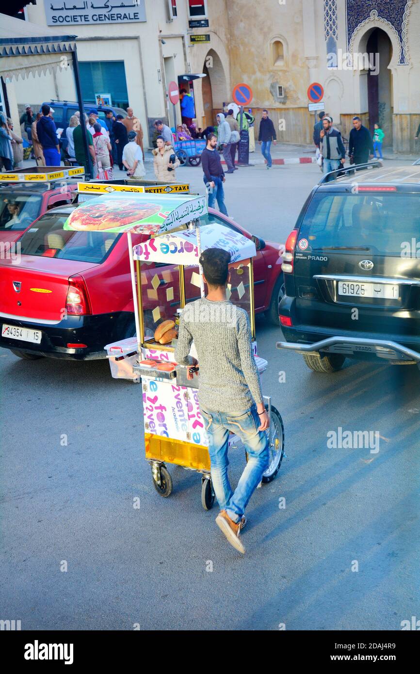 Fes, Morocco - November 20, 2014: Unidentified people and young man with trolley for snacks similar as hot dogs on way to souk fes el-Bali Stock Photo