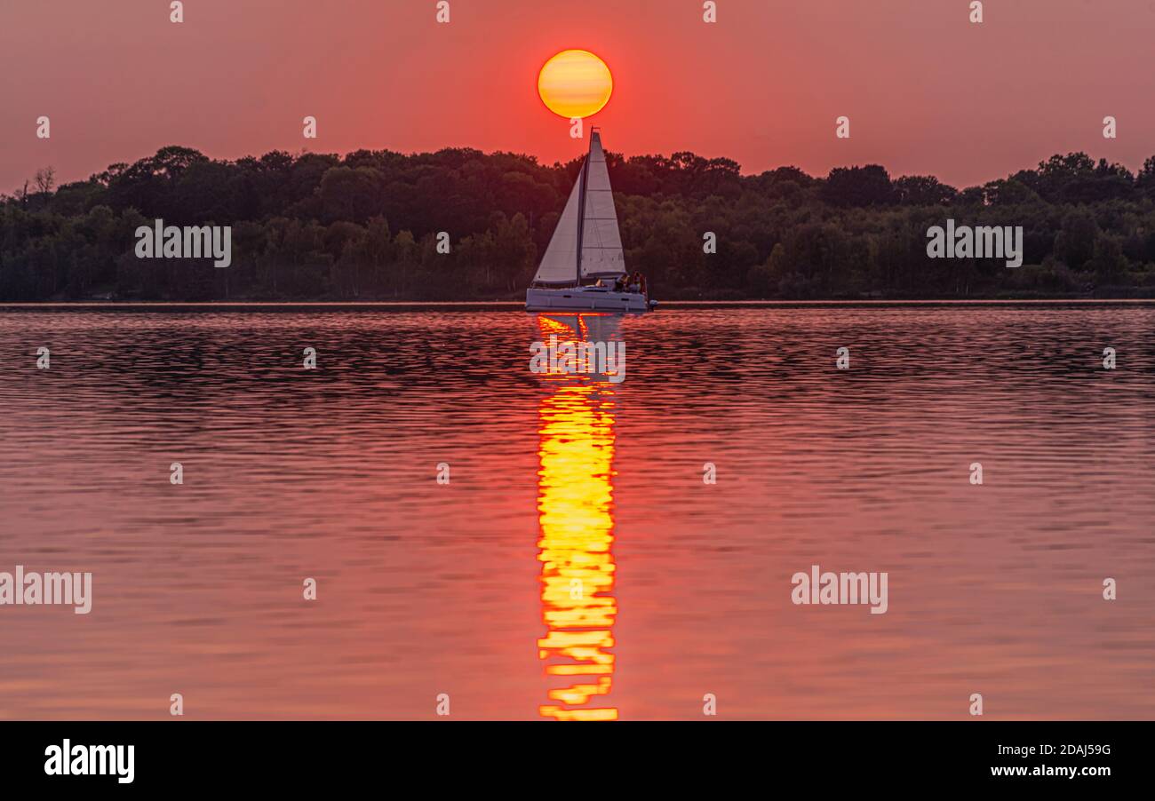 Sonnenuntergang am Cospudener See mit Segelboot und Sonnenball, Spiegelung im Wasser Stock Photo