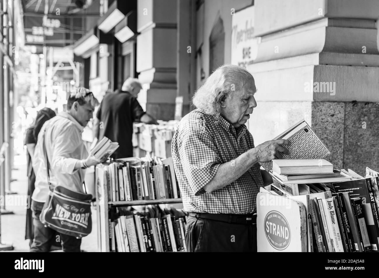 New York, USA - Sep 16, 2017: Black and white image of Strand Book Store in Manhattan. A gray-haired old man chooses a book to buy Stock Photo