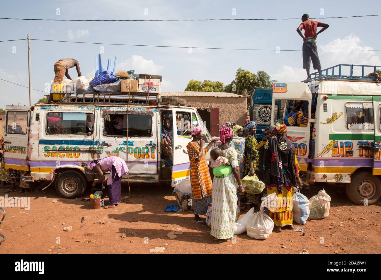 Selingue, Mali, 25th April 2015; Women wait to load their items onto a bus at the end of market day. Stock Photo