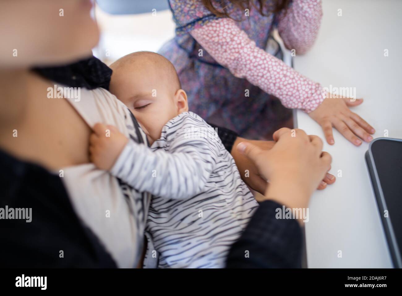 Sleeping baby resting in the arms of her mother while breastfeeding and