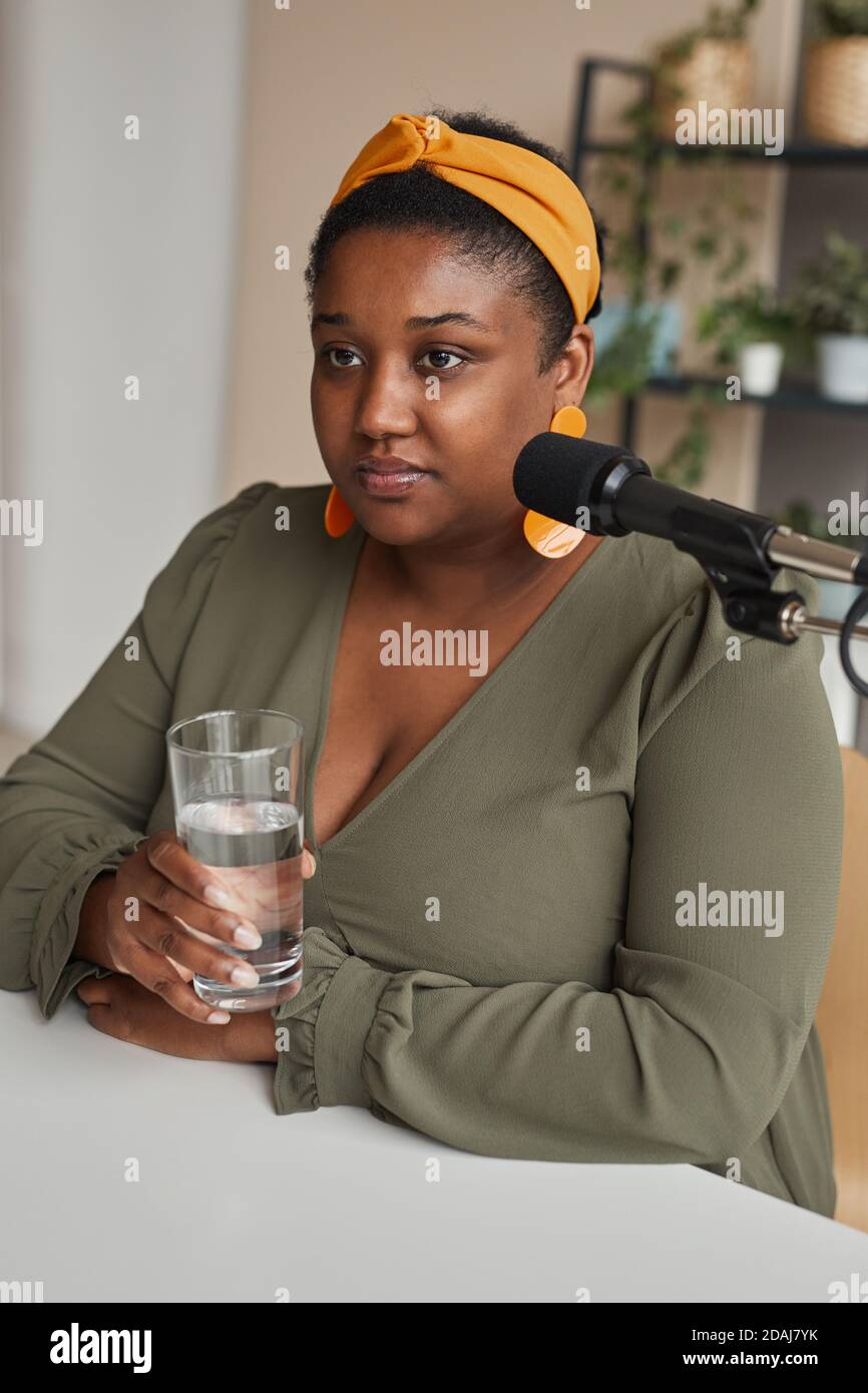 African elegant woman drinking water before her interview on the radio Stock Photo