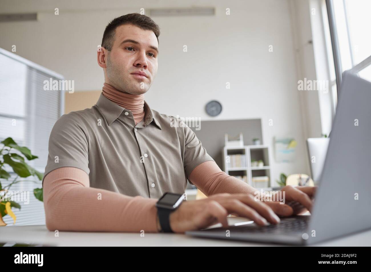 Computer programmer sitting at the table and typing on laptop computer at office Stock Photo
