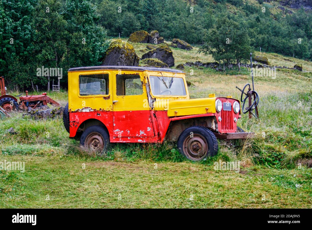 Old and weathered truck in yellow and red in rural landscape Stock Photo