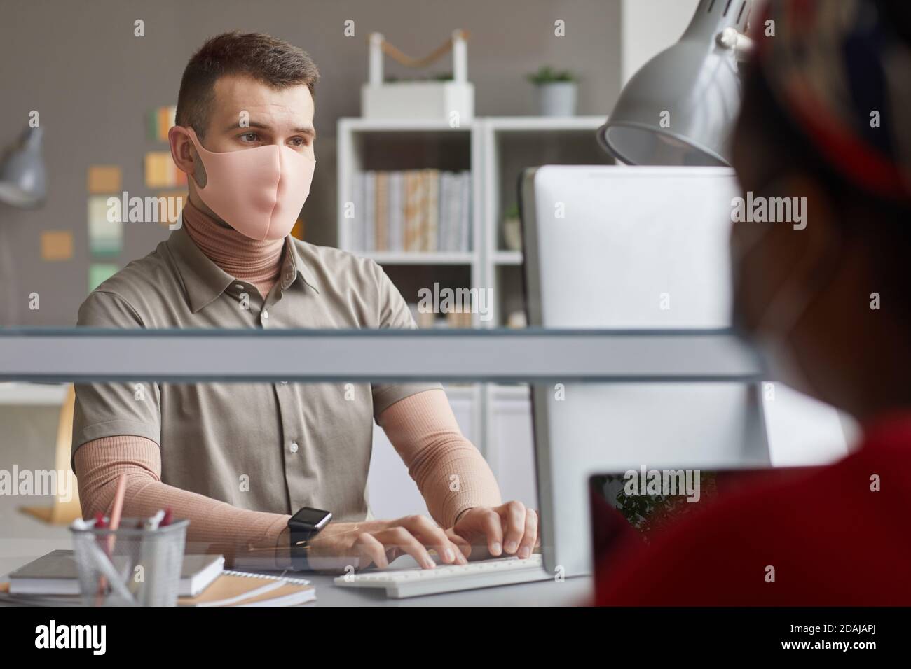 Young man in protective mask working at his workplace at office Stock Photo