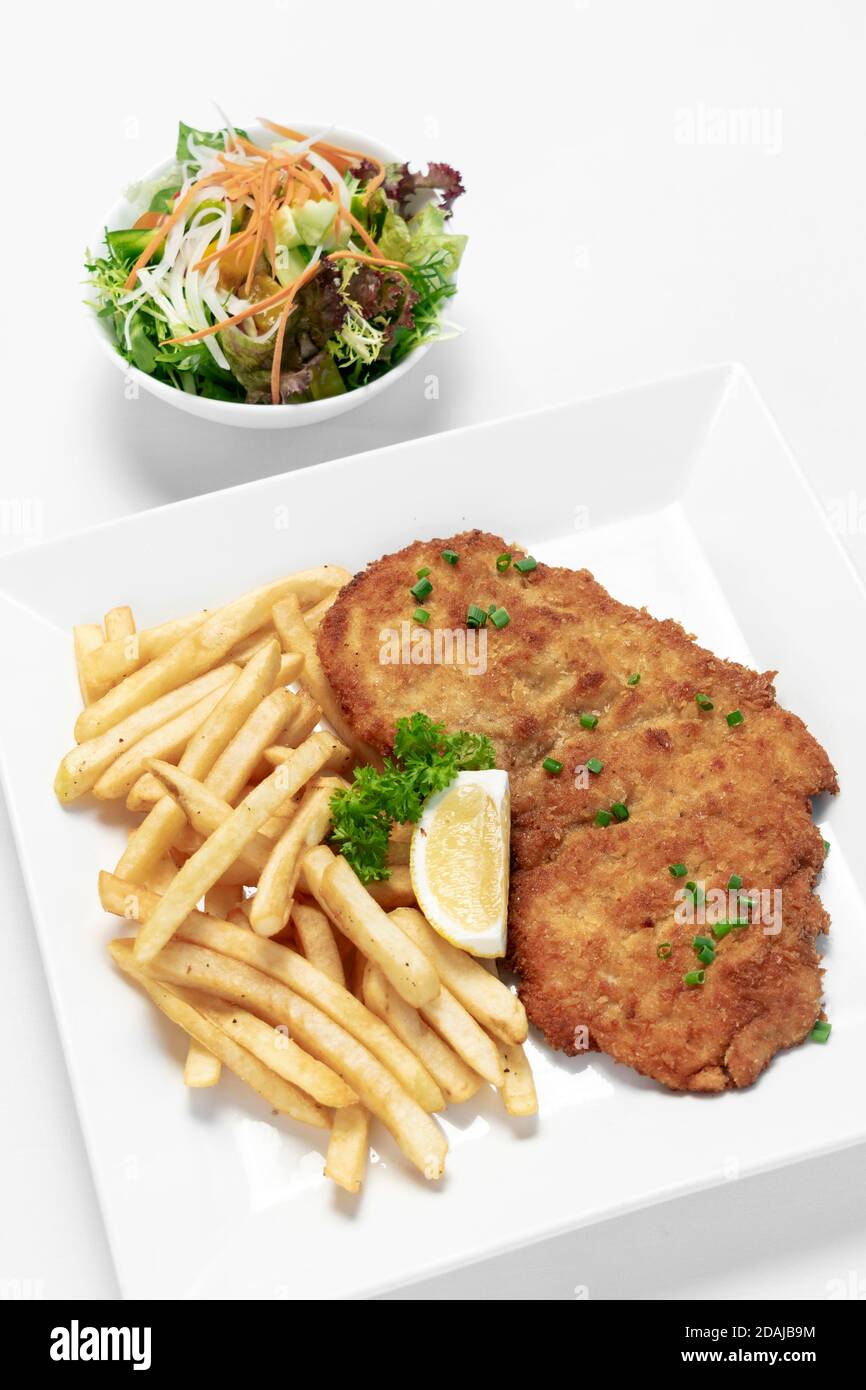 german breaded pork schnitzel with french fries on white studio background Stock Photo