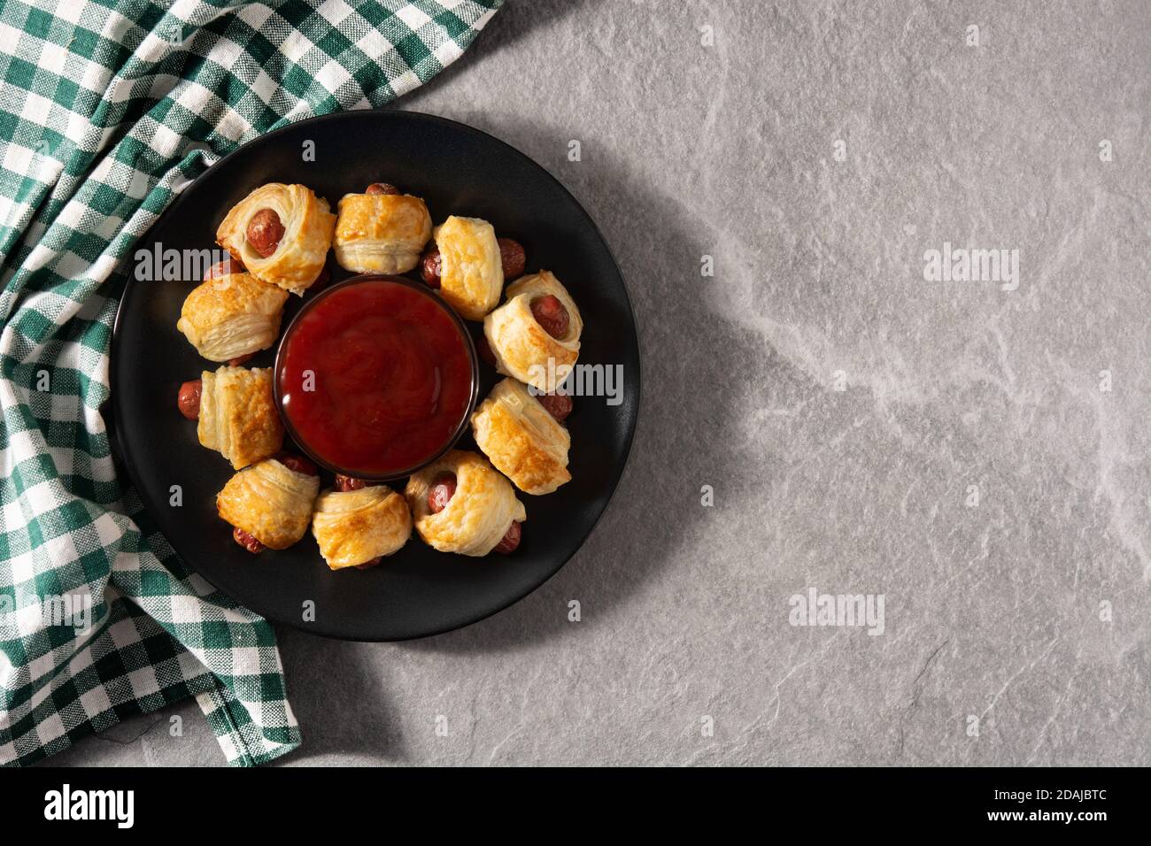 Pigs in blankets. Mini sausages wrapped in puff pastry with ketchup sauce on gray stone background Stock Photo
