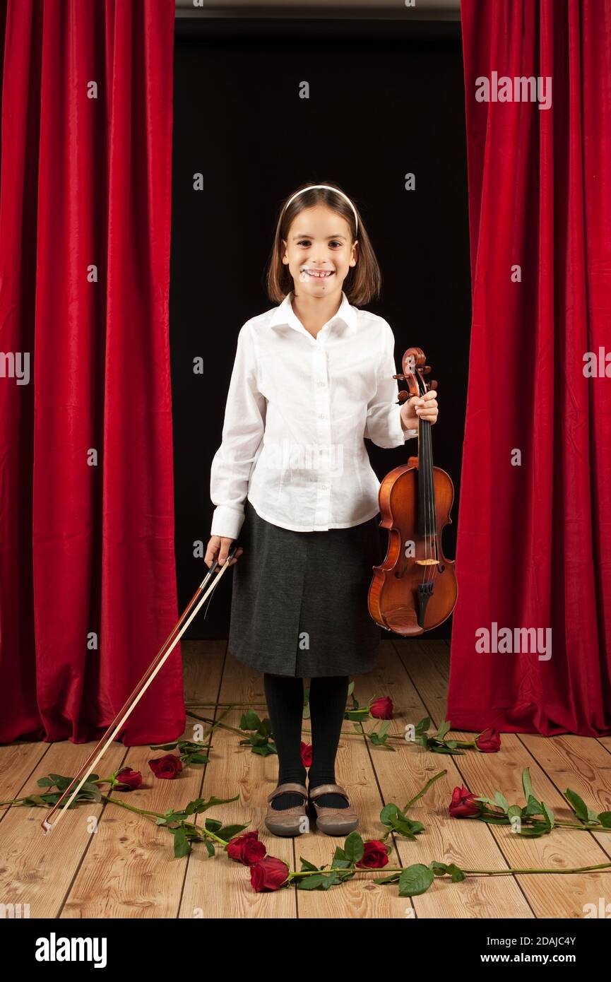 Little girl playing violin on stage theater Stock Photo - Alamy