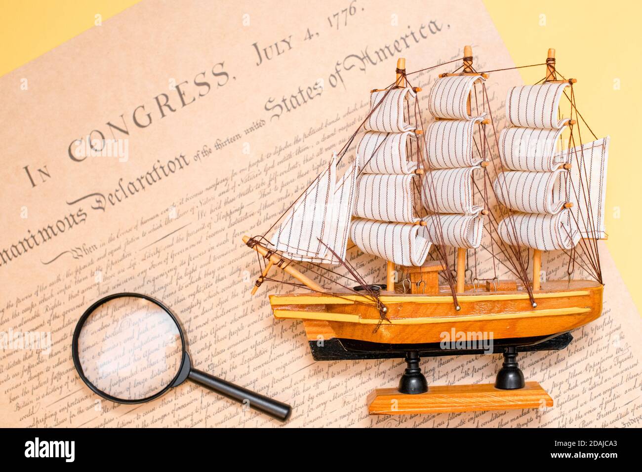 Ship made of wood and fabric handmade on the background of an excerpt from a copy of the document of 1776 on the signing of the independence of Stock Photo