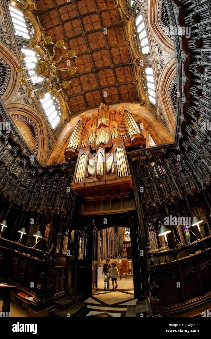 Inside the ornate, heavily wooden carved collegiate chancel of Manchester Cathedral interior including magnificent organ pipes and chandelier. Stock Photo