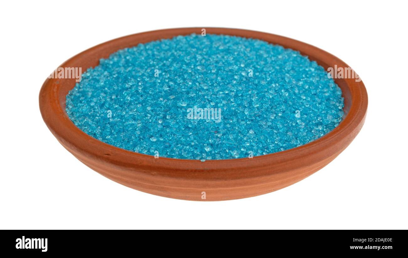 Portion of blue sanding sugar in a small clay bowl isolated on a white background. Stock Photo